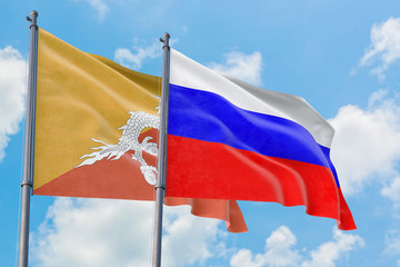 Russia and Bhutan flags waving in the wind against white cloudy blue sky together. Diplomacy concept, international relations.