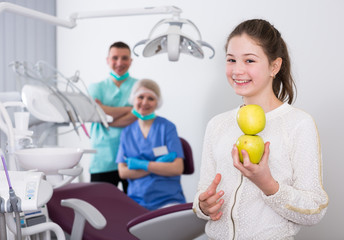 Happy girl with apples in dental clinic