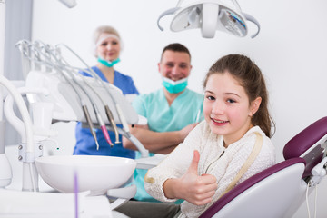Girl in dental chair giving thumbs up