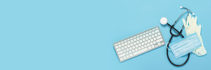 Keyboard, medical stethoscope, latex gloves and a protective mask on a blue background. Concept medicine, hospital, safety, epidemic, doctor's call, online, consultation. Banner. Flat lay, top view