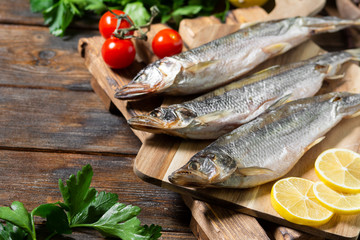 Smoked or dried smelt fish on a wooden Board on a brown wooden table. Top view with space for text