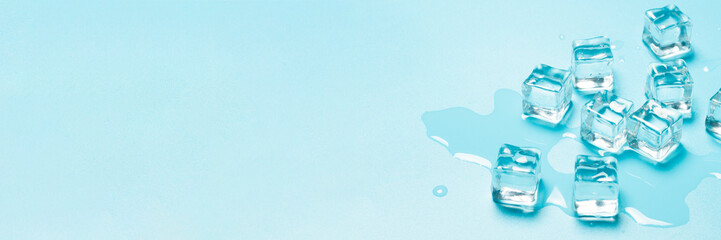 Ice cubes with water on a blue background. Ice concept for drinks. Banner. Flat lay, top view
