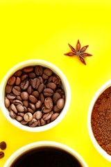 Three white cups with ground coffee, coffee beans and black brewed coffee in the rays of bright sunlight, sunset, dawn on a yellow background. Close-up, top view, flat lay, copy space for text.