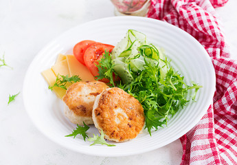 Ketogenic lunch. Chicken burger with tomato, cucumber, cheese and arugula salad without bun. Chicken patties. Healthy food. Keto/paleo diet.