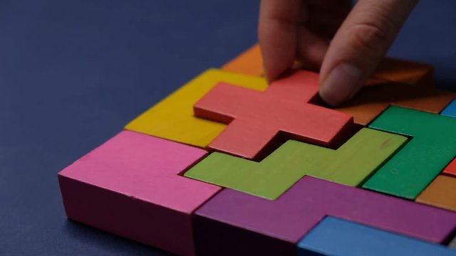 Closeup Slow motion. Hand holding piece of wooden block puzzle. wood cube stacking. Concept of complex and smart logical thinking. on a black background