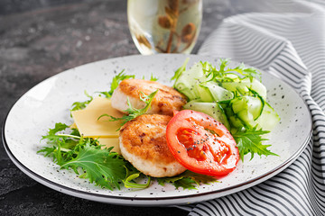 Ketogenic lunch. Chicken burger with tomato, cucumber, cheese and arugula salad without bun. Chicken patties. Healthy food. Keto/paleo diet.