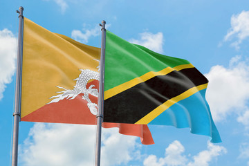 Tanzania and Bhutan flags waving in the wind against white cloudy blue sky together. Diplomacy concept, international relations.