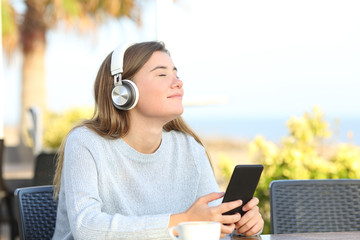 Relaxed girl is listening to music with headphones and phone