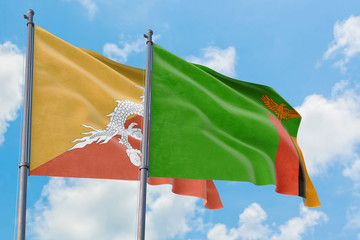 Zambia and Bhutan flags waving in the wind against white cloudy blue sky together. Diplomacy concept, international relations.