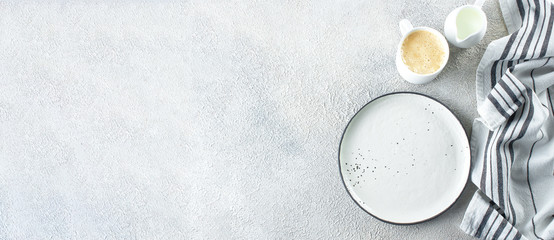 Empty ceramic plate, cup of coffee and kitchen striped towel on light stone concrete table background. Copy space. Menu Recipe Concept. Top view. Flat lay. Banner for design, website