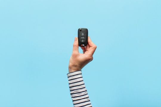Female hand holds car keys on a blue background. Concept car, car rental, gift, driving lessons, driving license. Banner. Flat lay, top view