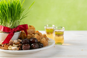 Nowruz holiday concept - grass, baklava sweets, nuts and seeds, copy space