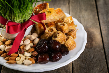 Nowruz holiday concept - grass, baklava sweets, nuts and seeds, copy space