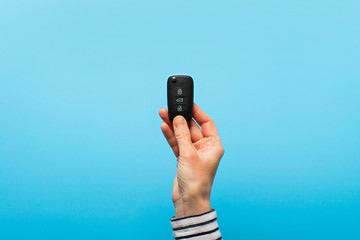 Female hand holds car keys on a blue background. Concept car, car rental, gift, driving lessons, driving license. Banner. Flat lay, top view