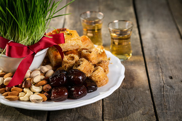 Nowruz holiday concept - grass, baklava sweets, nuts and seeds, copy space
