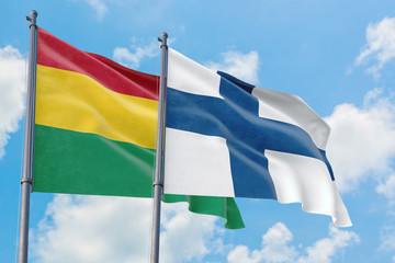 Finland and Bolivia flags waving in the wind against white cloudy blue sky together. Diplomacy concept, international relations.