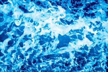 Aerial Ocean water surface with foam and waves behind of fast moving powerful engines.