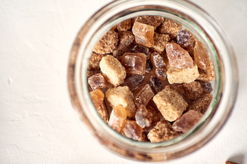 Brown cane sugar lump in a sugar bowl, top view. Concept diet, junk food, health.