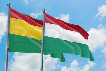 Hungary and Bolivia flags waving in the wind against white cloudy blue sky together. Diplomacy concept, international relations.