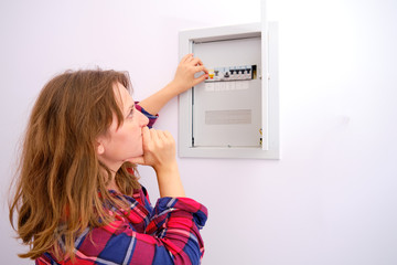 Woman thinking about turning on the switch in a household electrical panel