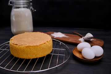 Fresh baked cake biscuit on black background, copy space. Wooden background, can of flour and metal rack