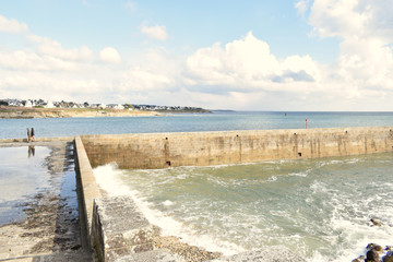 Audierne ville du Finistère en Bretagne sa baie son phare sa jetée le pont et les vagues qui se jettent sur les rochers en projetant de l'écume à marée haute