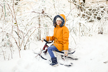 Fototapeta na wymiar child in yellow rides snow scooter in winter park