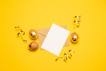 Craft envelope with a white sheet of paper and gold eggs on a yellow background