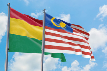 Malaysia and Bolivia flags waving in the wind against white cloudy blue sky together. Diplomacy concept, international relations.