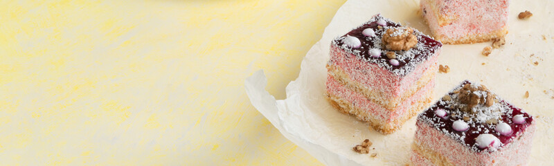 Delicious slices of cake with strawberry cream and coconut, yellow background, creamy dessert, holiday themes