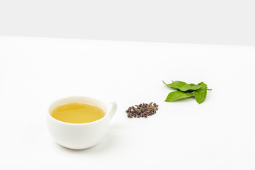 One cup of oolong tea with fresh leaves and a heap of dry green tea on a white background, with copy space for text. Organic herbal, green asian tea for the tea ceremony. Flat lay