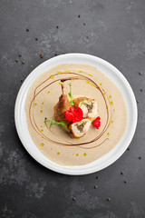 Stuffed duck leg with sauce, on a white plate, on a dark background