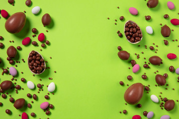 Egg hunt is coming. Easter traditions, chocolate eggs, candies on green background, top view, copyspace for your ad or greetings. Concept of holidays, spring, celebrating, food and sweets, family time