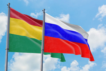 Russia and Bolivia flags waving in the wind against white cloudy blue sky together. Diplomacy concept, international relations.