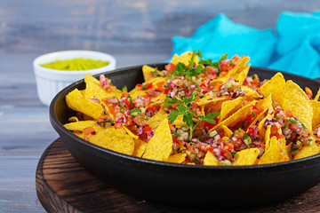 Mexican nachos with cheese. Corn chips with guacamole, salsa and tomato ketchup.
