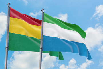 Sierra Leone and Bolivia flags waving in the wind against white cloudy blue sky together. Diplomacy concept, international relations.