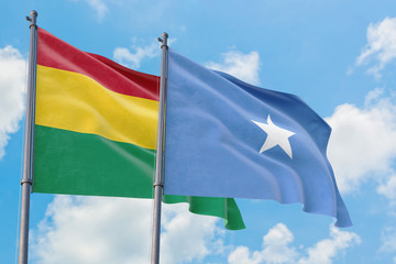 Somalia and Bolivia flags waving in the wind against white cloudy blue sky together. Diplomacy concept, international relations.