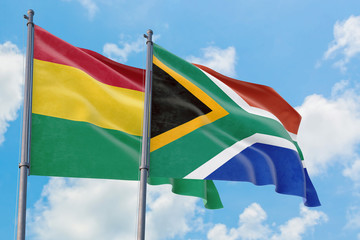 South Africa and Bolivia flags waving in the wind against white cloudy blue sky together. Diplomacy concept, international relations.