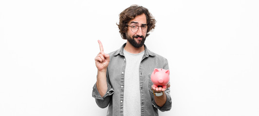 young crazy cool man holding a piggy bank against white wall