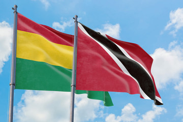 Trinidad And Tobago and Bolivia flags waving in the wind against white cloudy blue sky together. Diplomacy concept, international relations.