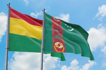 Turkmenistan and Bolivia flags waving in the wind against white cloudy blue sky together. Diplomacy concept, international relations.