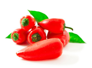 Sweet red peppers with green leaves isolated on a white background.