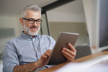 Mature man in office working with digital tablet