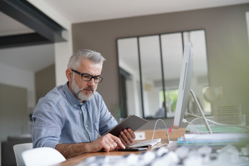 Mature man in office working with digital tablet