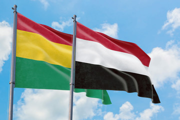 Yemen and Bolivia flags waving in the wind against white cloudy blue sky together. Diplomacy concept, international relations.