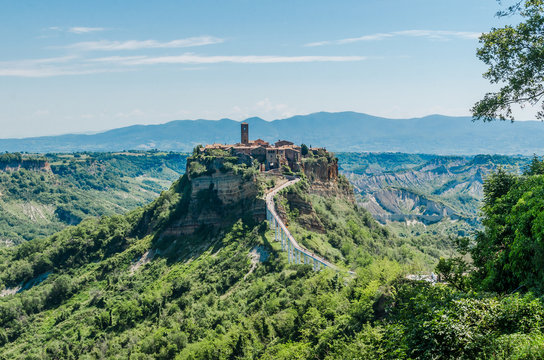The small italian town of Civita di Bagnoregio on top of a hill, immersed in a beautiful landscape, during a sunny day.