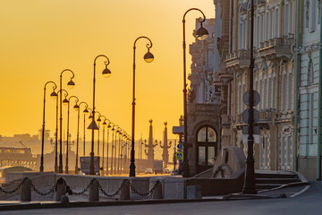 Saint Petersburg. Russia. Palace embankment against the yellow sky. Streetlights Of St. Petersburg. Early morning in St. Petersburg. Urban yellow-gray landscape. Embankment of the Neva river.