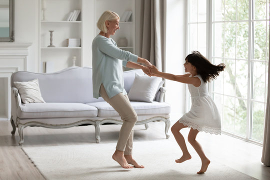 Energetic grandmother have fun dancing with little granddaughter