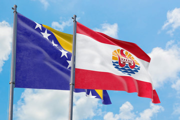 French Polynesia and Bosnia Herzegovina flags waving in the wind against white cloudy blue sky together. Diplomacy concept, international relations.
