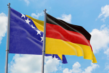Germany and Bosnia Herzegovina flags waving in the wind against white cloudy blue sky together. Diplomacy concept, international relations.